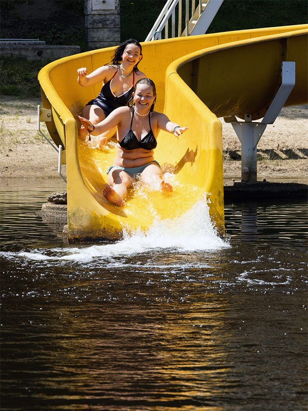 Deux vacancières profitent du toboggan aquatique du lac au Domaine du Lac de Soursac en Corrèze